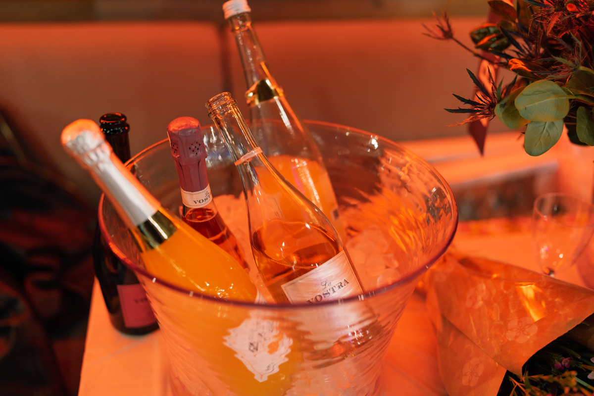 Bottles of bubbly chilling in an ice bucket beside a floral arrangement at the Lu Hickman Creative Co. anniversary soirée